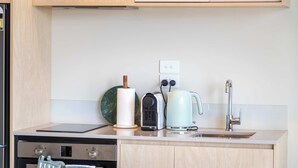 Una cocina moderna con horno empotrado, hervidor, tostadora y pileta.