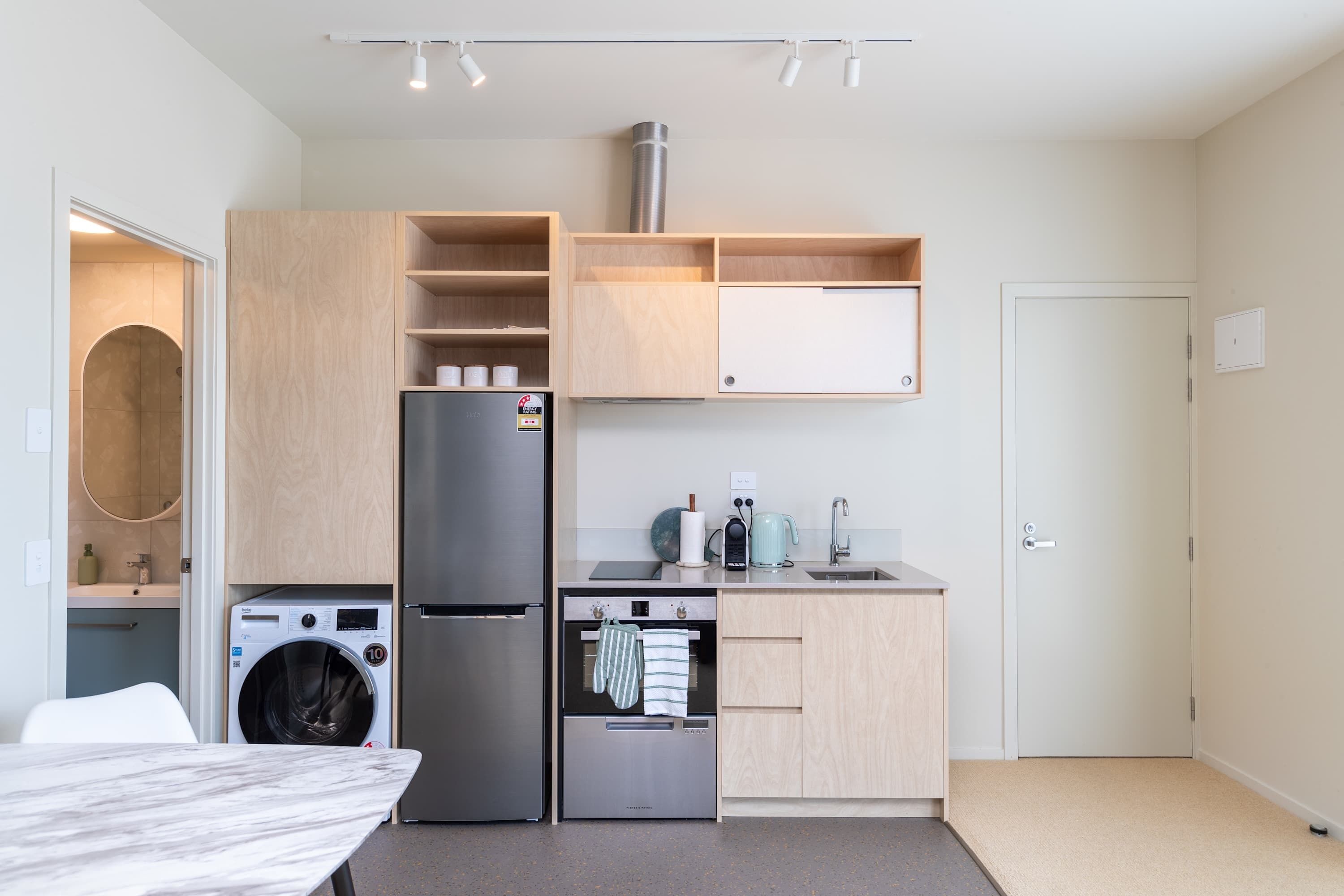 A compact kitchen with a washing machine, refrigerator, oven, and a sink.