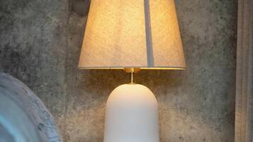 A white bedside table with a lamp and a power outlet.