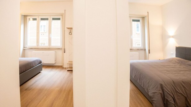 Una stanza con un letto, un divano, un termosifone e una finestra.
