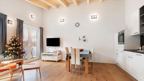 Ein modernes Wohnzimmer mit Essbereich, einer Küche, einem Fernseher und einem Weihnachtsbaum.