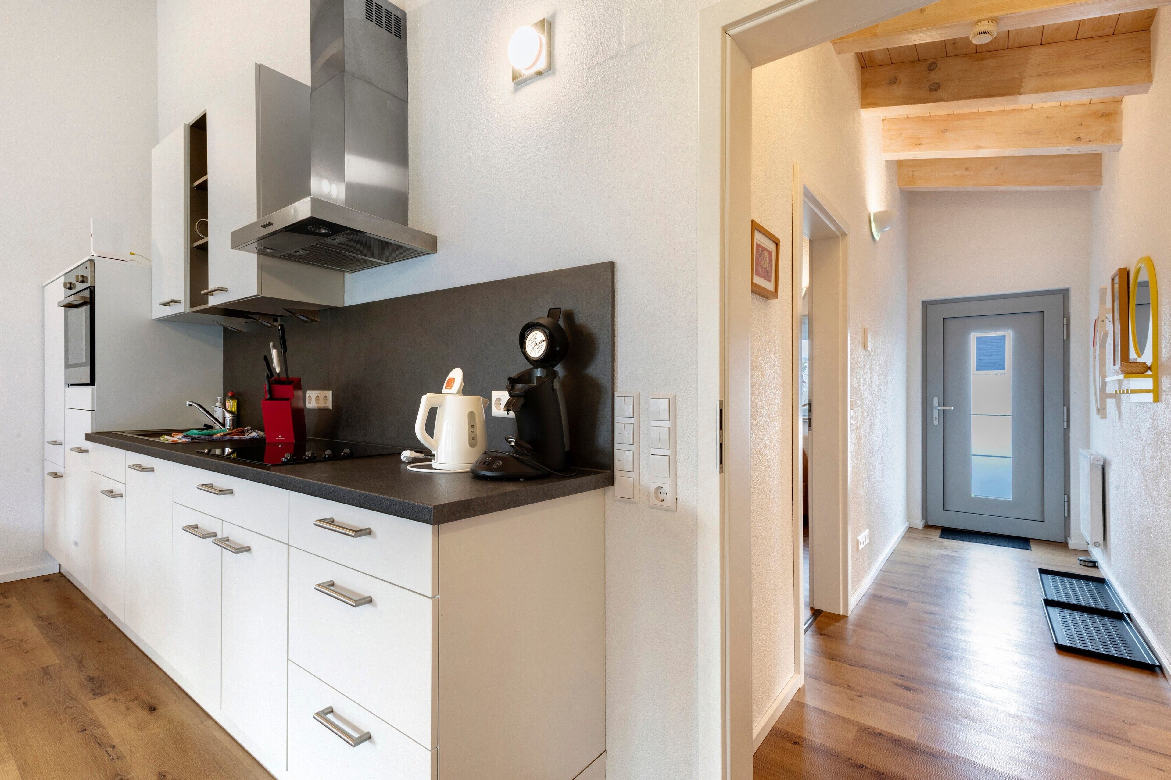 Una cocina moderna con armarios blancos, electrodomésticos de acero inoxidable y una cafetera.