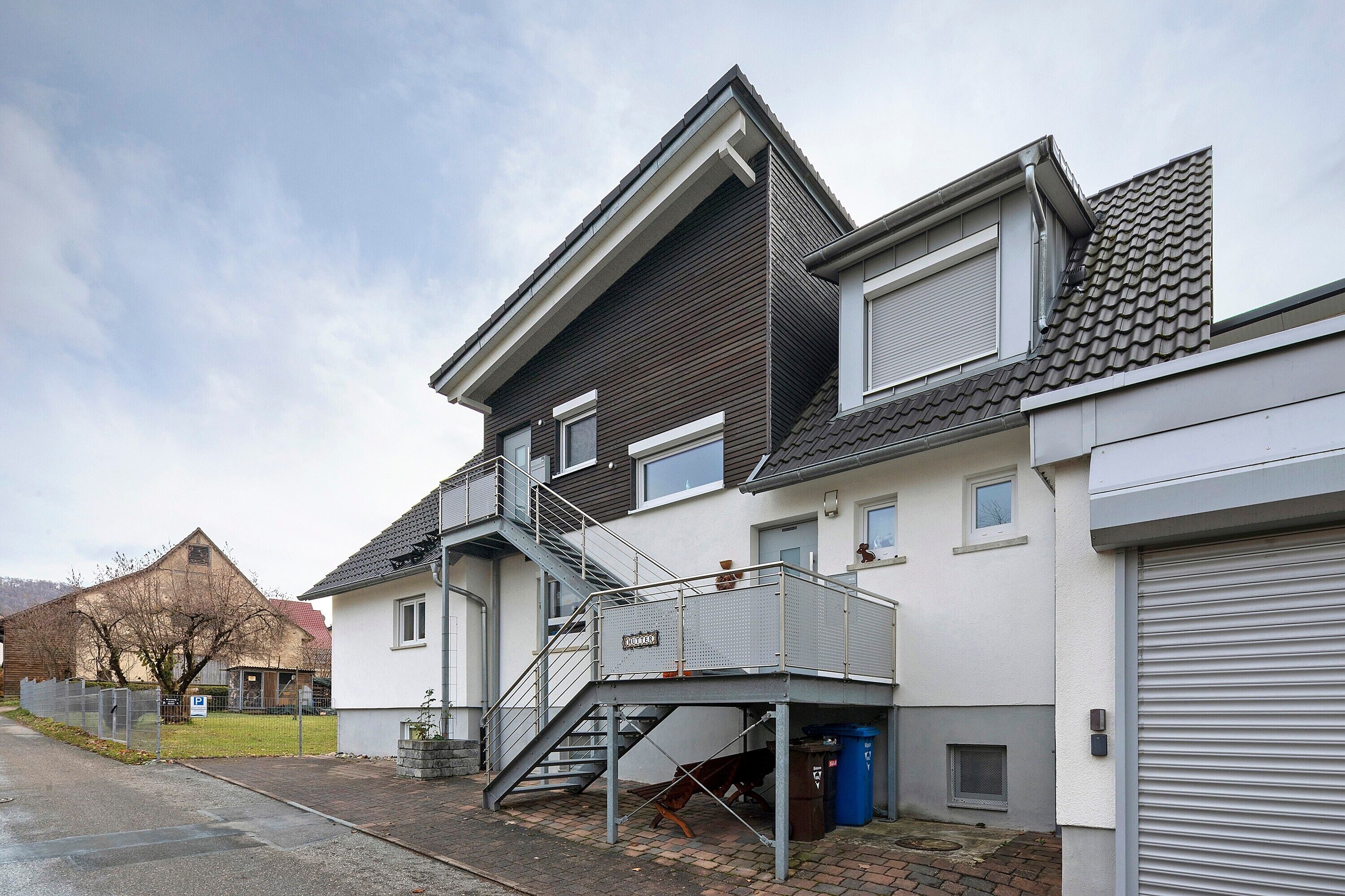 Un immeuble résidentiel de deux étages, doté d’un escalier en métal, d’une porte de garage et d’une petite fenêtre.