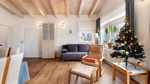 Ein modernes Wohnzimmer mit Holzboden, einem grauen Sofa, einer Holzbank und einem Weihnachtsbaum.
