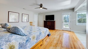 A bedroom with a bed, a ceiling fan, a dresser, a TV, and a door leading to a balcony. - New Listing, Spacious, King Beds, Linens Provided, Pool Table, KD1310 (Kill Devil Hills)