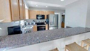 A modern kitchen with granite countertops, stainless steel appliances, and wooden cabinets. - New Listing, Spacious, King Beds, Linens Provided, Pool Table, KD1310 (Kill Devil Hills)