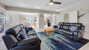 A spacious living room with a black leather sofa, a wooden coffee table, and a blue patterned rug. - New Listing, Spacious, King Beds, Linens Provided, Pool Table, KD1310 (Kill Devil Hills)