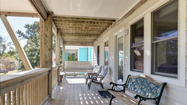 A covered porch with wooden railings, a bench, and chairs. - New Listing, Spacious, King Beds, Linens Provided, Pool Table, KD1310 (Kill Devil Hills)