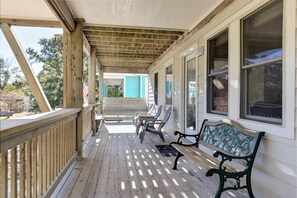 A covered porch with wooden railings, a bench, and chairs. - New Listing, Spacious, King Beds, Linens Provided, Pool Table, KD1310 (Kill Devil Hills)
