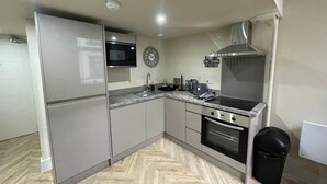 Une cuisine moderne avec des meubles gris, un four à micro-ondes, une cuisinière et un évier.