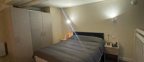 Et soveværelse med seng, to sengeborde, et klædeskab og en loftlampe.