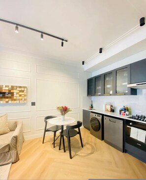 Uma cozinha moderna com área de jantar, com uma mesa redonda e cadeiras, um sofá e uma peça decorativa na parede.