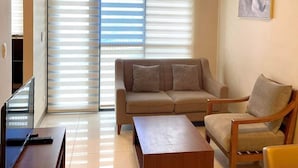 A modern living room with a sofa, armchair, coffee table, and a TV. - Studio Seaview at Mactan Newtown  (Lapu-Lapu)