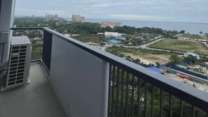 A balcony with a view of a coastal area, including buildings and greenery. - Studio Seaview at Mactan Newtown  (Lapu-Lapu)