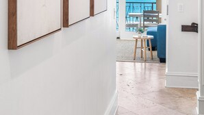 Ein Flur mit gerahmten Kunstwerken, der zu einem Balkon mit Meerblick führt.