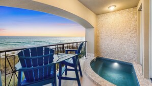 Ein Balkon mit Blick auf den Ozean, ein Schwimmbad und blaue Stühle.