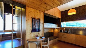 Una cocina moderna con muebles de madera, un comedor con mesa y sillas, un banco empotrado y un amplio ventanal con vistas al exterior.