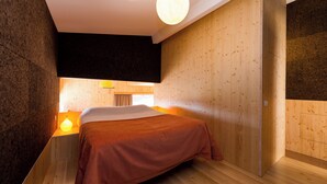 Un dormitorio moderno con cama, paredes de madera, una lámpara de techo y una mesita de noche con lámpara.