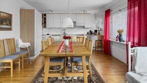 Una cocina moderna con armarios blancos, una mesa de comedor de madera y sillas, y un tratamiento de ventana rojo.