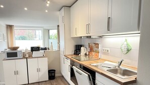 Een moderne keuken met witte kastjes, een houten aanrecht, een ingebouwde oven en een roestvrijstalen spoelbak.