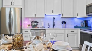 Une cuisine moderne avec des meubles blancs, des appareils en acier inoxydable et un coin repas aménagé pour prendre un repas.