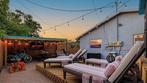 Un espace patio aménagé avec des chaises longues, une table et un panneau indiquant « SOIRÉE CINÉMA ».
