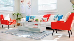 Un salon moderne avec un canapé blanc, des fauteuils rouges et une table basse.