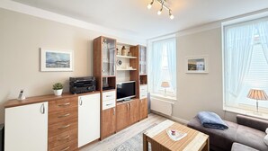 Een moderne woonkamer met een houten kast, televisie en een gezellige bank.