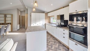 A modern kitchen with white cabinets, a central island, and stainless steel appliances. - Host Stay Beryl Lodge (York)