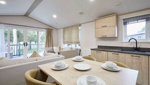 A modern kitchen with a dining area, wooden cabinets, and a large window. - Host Stay Hideaway Retreat (York)