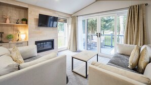 A modern living room with a fireplace, a flat-screen TV, and a sliding glass door leading to an outdoor area. - Host Stay Hideaway Retreat (York)