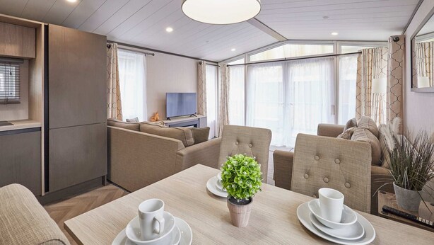 A modern, well-lit room with a dining table set for two, a television in the background, and comfortable seating. - Host Stay Royal Pines Lodge (York)