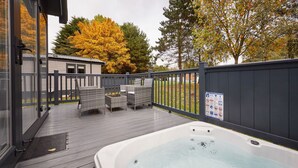 A hot tub on a wooden deck with outdoor furniture and a fenced area. - Host Stay Royal Pines Lodge (York)
