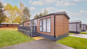 A modern mobile home with a wooden exterior, a front porch, and a visible staircase leading to the entrance. - Host Stay Royal Pines Lodge (York)