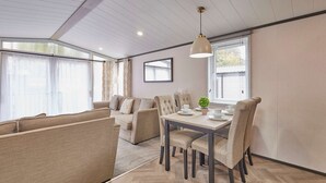 A modern living room with a sofa set, dining table, and chairs. - Host Stay Royal Pines Lodge (York)