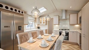 Una cocina moderna con una isla central, electrodomésticos de acero inoxidable e iluminación colgante.