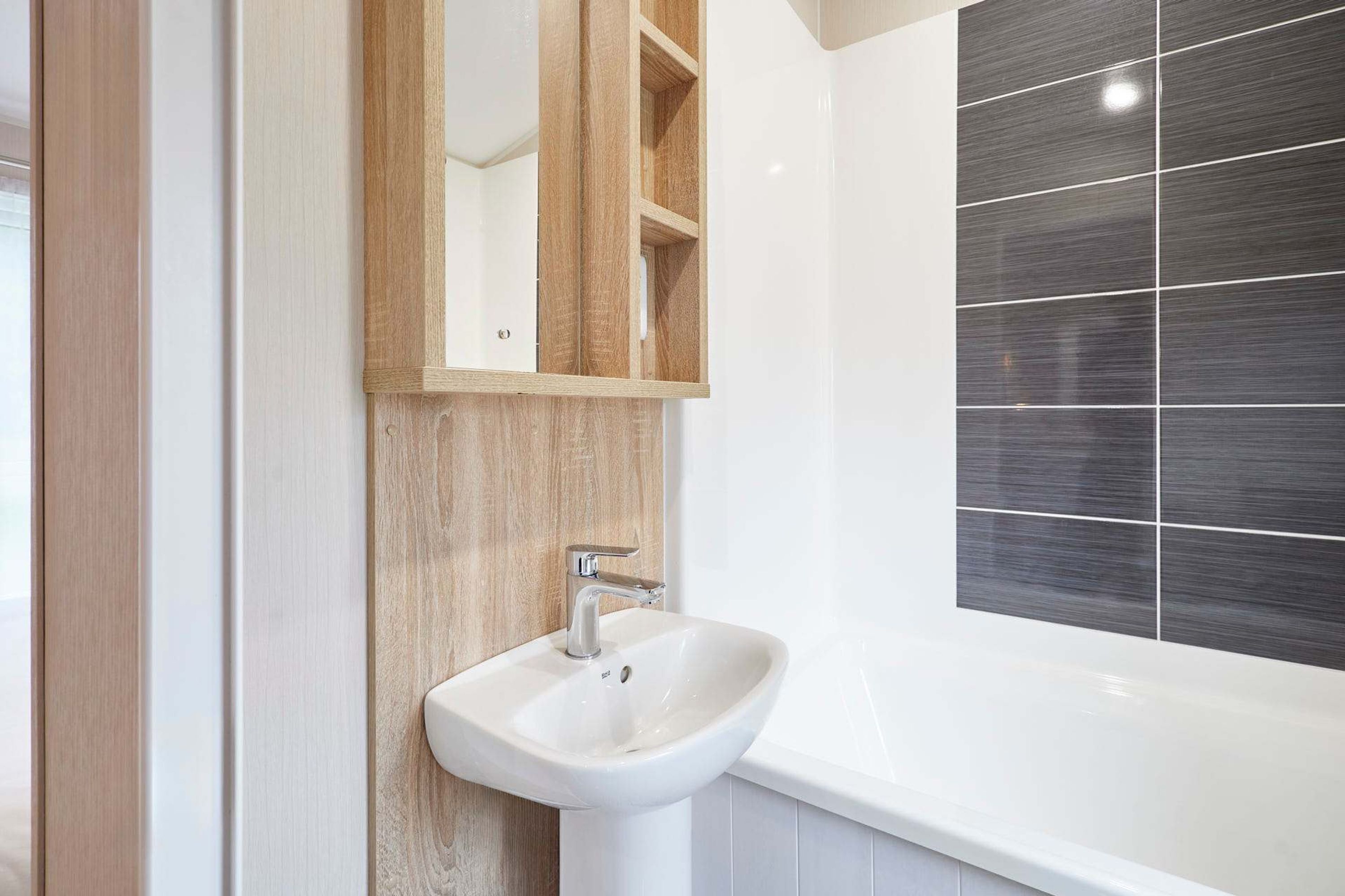 A bathroom with a white sink, wooden cabinet, and a large mirror.