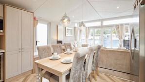 Un comedor moderno con una mesa de madera, sillas acolchadas e iluminación colgante.