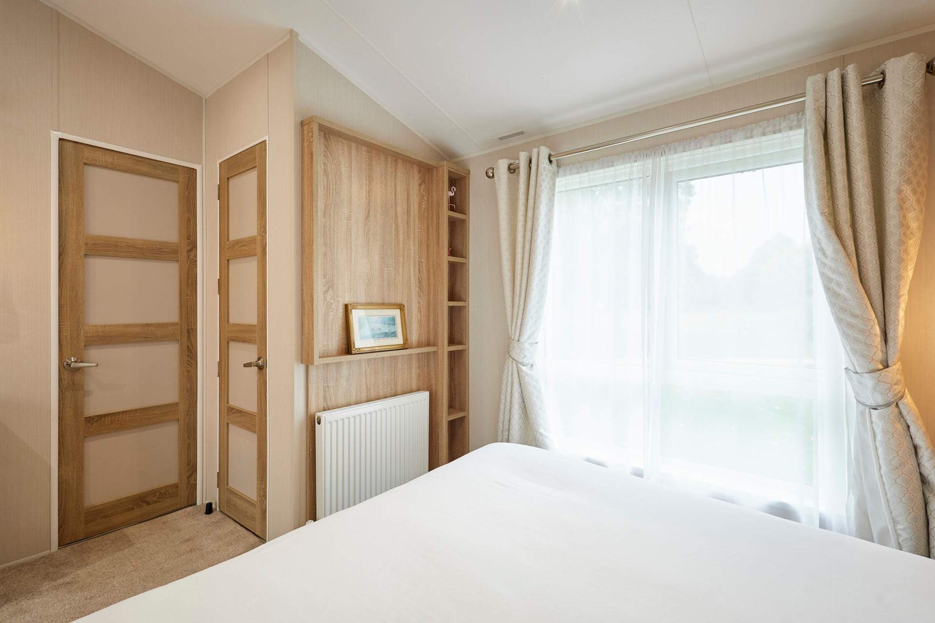 Une chambre à coucher avec un lit, une armoire, un radiateur et une fenêtre avec des rideaux.