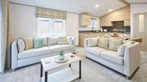 A modern living room with two sofas, a coffee table, and a kitchen in the background. - Host Stay Wag Tail Lodge (York)