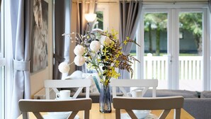 Ein Esstisch mit weißen Stühlen und einer Blumenvase.