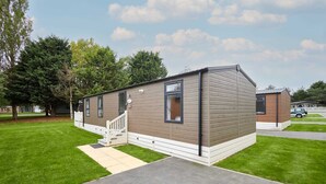 Ein Bungalow mit Veranda, einer kleinen angebauten Garage und einem gepflegten Rasen.