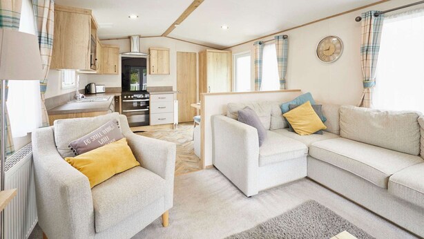 A modern, well-lit living area with a sofa set, a dining table, and a kitchen area. - Host Stay Squirrel Lodge (York)