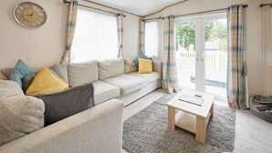 A cozy living room with a sofa, a coffee table, and curtains. - Host Stay Squirrel Lodge (York)