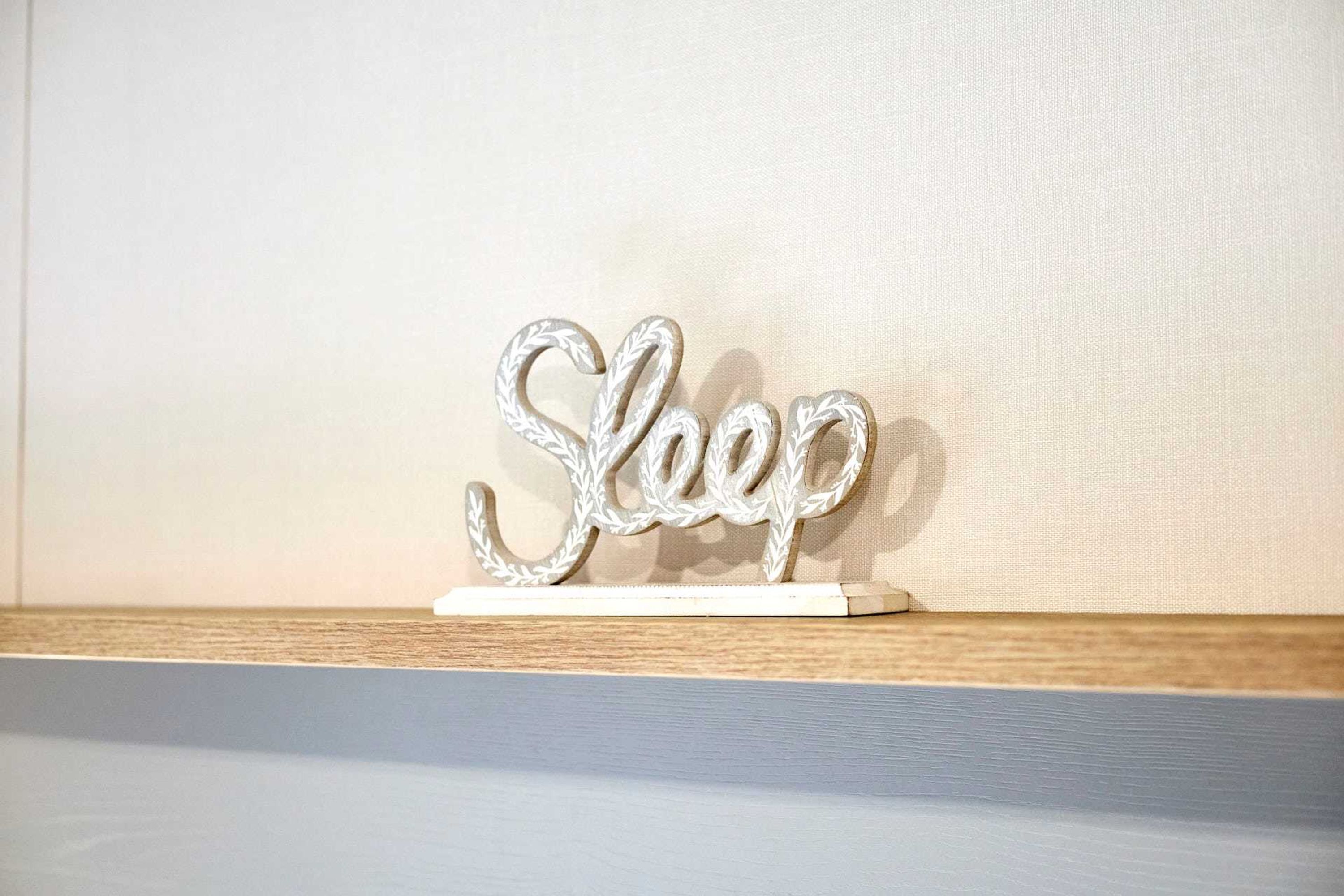 Koristeellinen kyltti, jossa on sana ”Sleep”, hyllyllä.