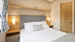 A neatly arranged bedroom with a bed, bedside lamps, a wooden headboard, a wardrobe, and a sign above the bed that says "Sleep". - Host Stay Squirrel Lodge (York)