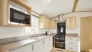 A modern kitchen with a built-in microwave, oven, and sink. - Host Stay Squirrel Lodge (York)
