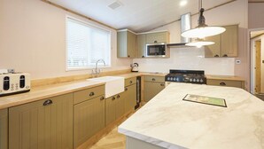 A modern kitchen with wooden cabinets, a built-in microwave, a stove, and a large marble island. - Host Stay Hawthorne Villa (York)