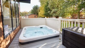 A hot tub on a wooden deck with a white fence and trees in the background. - Host Stay Hawthorne Villa (York)