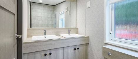 A modern bathroom with two sinks, a large mirror, and a window.